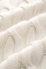 Nahaufnahme des Moorer Rollkragenpullover 'Gordon' creme, perspektivisch von schräg oben, mit grobem Zopfmuster aus Wolle-Cashmere-Mix.