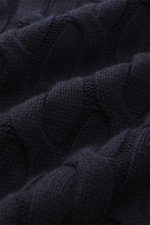 Nahaufnahme des Moorer Rollkragenpullover 'Gordon' navy aus Wolle-Cashmere-Mix mit grobem Zopfmuster, weichem Griff, Regular Fit, Rollkragen und flexiblen Rippbündchen, fotografiert aus schräger Perspektive.