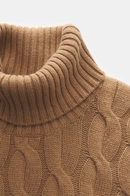 Nahaufnahme des Moorer Rollkragenpullovers 'Gordon' hellbraun mit klassischem Zopfmuster, weichem Woll-Cashmere-Mix und anliegendem Rollkragen, aus leichter Perspektive fotografiert.