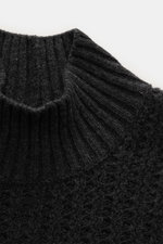 Nahaufnahme des Closed Mock-Neck Pullover dunkelgrau meliert aus edlem Wollstrick mit markantem Strukturstrick, Rippkragen und Rippbündchen, fotografiert von oben.