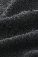 Nahaufnahme des feinen Strickbilds eines dunkelgrau melierten BRAUN Hamburg Cashmere Rundhalspullover mit weichem Griff, fotografiert aus der Nähe.