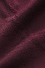 Nahaufnahme des von Braun Merino Feinstrick-Rollkragenpullovers bordeaux aus reiner Merinowolle, feines Strickbild, weicher Griff, Slim Fit, anliegender Rollkragen, flexible Rippbündchen, von oben fotografiert.