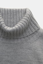 Nahaufnahme des hellgrauen von Braun Merino Rollkragenpullovers mit mittelfeinem Strickbild, flexiblem Rippbündchen und Rollkragen aus Rippstrick, fotografiert von oben.