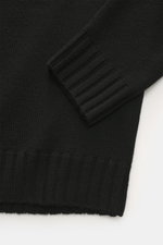 Nahaufnahme aus schräger Perspektive des von Braun Merino Rollkragenpullover schwarz mit mittelfeinem Strickbild, Rippstrick-Rollkragen und flexiblen Rippbündchen aus reiner Merinowolle.