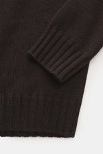 Nahaufnahme des von Braun Merino Rollkragenpullover braun, fotografiert aus seitlicher Perspektive, mittelfeines Strickbild, Rollkragen und flexible Rippbündchen sichtbar.