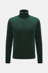 Frontale Nahaufnahme des dunkelgrünen von Braun Merino Rollkragenpullovers mit mittelfeinem Strickbild, Oversized Fit und Rippstrick-Kragen.
