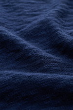 Close-up fabric texture of the 04651/ A trip in a bag Crew neck jumper navy, showing soft pure cotton with fine knit, flammé effect, and stretchy knit bands from an angled macro perspective. Ideal for warmer days, this regular fit spring staple features a