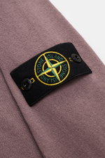 Stone Island Rundhalspullover flieder in Slim Fit, aus reiner Baumwolle mit feinem Strickbild, rolliertem Saum, Rundhalsausschnitt und Kompass-Badge, Nahaufnahme.
