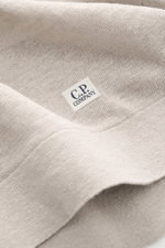 Nahaufnahme des C.P. Company Kurzarmpullovers grau aus feinstem Leinenstrick, weicher Griff, feines Strickbild, mit kleinem Weblabel am Saum.