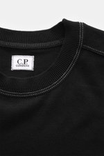 Nahaufnahme des schwarzen C.P. Company Rundhalspullover schwarz von oben, zeigt gerippten Rundhalsausschnitt mit weißen Kontrastnähten und Markenlabel.