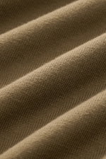 Nahaufnahme des feinen Strickbilds eines olivfarbenen C.P. Company Rundhalspullover aus weicher Baumwolle, Detail von oben.