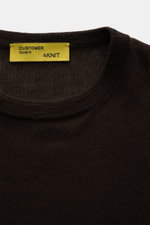 Nahaufnahme aus schräger Draufsicht des B.F. Knitwear Cashmere Rundhalspullover dunkelbraun mit rundem Ausschnitt, feinem, luftigen Strickbild und elastischen Bündchen.