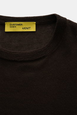 Nahaufnahme aus schräger Draufsicht des B.F. Knitwear Cashmere Rundhalspullover dunkelbraun mit rundem Ausschnitt, feinem, luftigen Strickbild und elastischen Bündchen.
