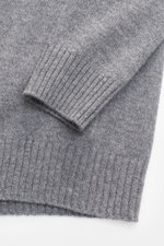 Nahaufnahme des von Braun Cashmere Rundhalspullover grau meliert, fotografiert von oben, zeigt mittelfeines Strickbild, elastische Rippbündchen, Slim Fit, Rundhalsausschnitt, weiches, reines Cashmere aus Innerer Mongolei.