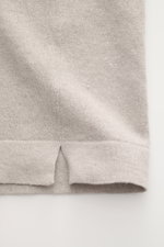 Close-up of the hem with short vents of the 04651/ A trip in a bag Fine knit short sleeve jumper 'Pocket Tee' taupe, showcasing its fine linen-cotton knit and double-layered hems, photographed from the side.

Description: Lightness you can feel: The fine 