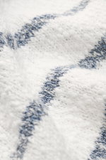 Nahaufnahme des grob gestrickten 04651/ A trip in a bag Rundhalspullover 'Mouline Striped' offwhite/navy gestreift mit klassischem Streifenmuster, Rundhalsausschnitt und Rippbündchen aus reiner Baumwolle, perspektivisch von oben fotografiert.