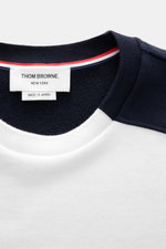 Nahaufnahme des Thom Browne Rundhals-Sweatshirt weiß/navy mit weichem Baumwollstoff, Rippbündchen und tricolor Grosgrain-Schlaufe am Kragen.