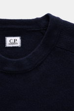C.P. Company Rundhalspullover navy, Detailaufnahme von oben, mittelfeines Strickbild, weicher Griff, Rundhalsausschnitt, Label innen sichtbar.