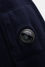 Nahaufnahme des navyfarbenen C.P. Company Rundhalspullover mit mittelfeinem Strickbild und ikonischer Ärmel-Tasche mit Zipper, seitlich fotografiert.