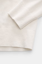 Nahaufnahme des Ärmel- und Bundbereichs vom C.P. Company Rundhalspullover offwhite mit mittelfeinem Strickbild und flexiblen Rippbündchen.