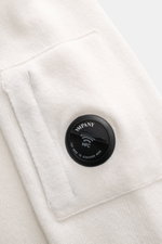 Nahaufnahme des Ärmel-Details mit Tasche und NFC-Linse des C.P. Company Rundhalspullover offwhite, mittelfeines Strickbild, weicher Griff.