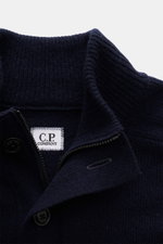 Nahaufnahme des C.P. Company Troyer navy aus weicher Schurwolle, mittelfeines Strickbild, Troyer-Kragen mit Knöpfen, Zipper, von oben fotografiert.
