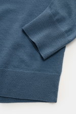 C.P. Company Rundhalspullover graublau, Detailaufnahme von Ärmel und Bund, feiner Woll-Mix, weiches Strickbild, Rippbündchen, Linsen-Detail am Ärmel.