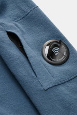 C.P. Company Rundhalspullover graublau, Nahaufnahme von Ärmel mit feinem Strick, Zipper-Tasche und labeltypischem Linsen-Detail, weicher Woll-Mix.