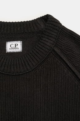 Nahaufnahme des schwarzen C.P. Company Rundhalspullovers aus Baumwoll-Chenille, Fokus auf Rundhalsausschnitt und labeltypisches Linsen-Detail.