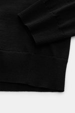 Nahaufnahme des Stone Island Rundhalspullover 'Ghost Piece' schwarz aus reiner Wolle, Slim Fit, weiche Rippbündchen, feines Strickbild, von oben fotografiert.