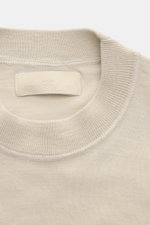 Stone Island Rundhalspullover 'Ghost Piece' beige, Detailaufnahme von oben, reine Wolle, weicher Griff, feines Strickbild, tonales Kompass-Badge am Ärmel.