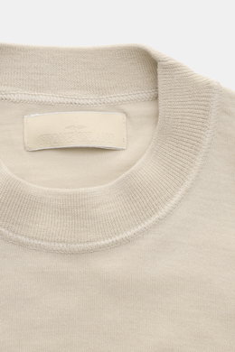 Stone Island Rundhalspullover 'Ghost Piece' beige, Detailaufnahme von oben, reine Wolle, weicher Griff, feines Strickbild, tonales Kompass-Badge am Ärmel.