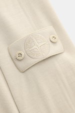 Nahaufnahme des tonalen Kompass-Badges am Ärmel des Stone Island Rundhalspullover 'Ghost Piece' beige aus feiner Wolle, weich und leicht, mit feinem Strickbild, Rippbündchen, aufgenommen aus seitlicher Perspektive.