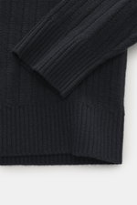 Nahaufnahme des Stone Island Rundhalspullover 'Ghost Piece' navy, Slim Fit mit mittelfeinem Strickbild, weichem Griff, Rundhalsausschnitt, elastischen Rippbündchen und tonalem Kompass-Badge am Oberarm, fotografiert von schräg oben.