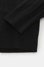 Nahaufnahme des Stone Island Rundhalspullover 'Ghost Piece' schwarz von oben, zeigt weichen Griff, Slim Fit, Rundhalsausschnitt, mittelfeines Strickbild, tonales Kompass-Badge am Oberarm und elastische Rippbündchen, Mix aus Schurwolle und Cashmere.
