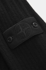 Nahaufnahme des tonalen Kompass-Badges am Oberarm des Stone Island Rundhalspullover 'Ghost Piece' schwarz, Mix aus Schurwolle und Cashmere, weicher Griff, mittelfeines Strickbild, Slim Fit, Rundhalsausschnitt, elastische Rippbündchen, seitliche Perspektiv