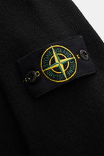 Close-up view of the sleeve of Stone Island Crew Neck Sweater 'Lambswool' Black showing the black link-knit texture and iconic compass badge.

Description: 
<p>Stylish essential for the cold season: This casual sweater by STONE ISLAND made from a warming 