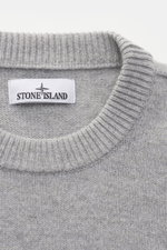Stone Island Crew Neck Sweater 'Lambswool' Light Grey shown close-up from above, soft virgin wool blend, medium-fine knit, ribbed cuffs, and crew neckline. Stylish essential for cold season with distinctive link-knit details and iconic compass badge on th