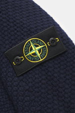 Nahaufnahme des Stone Island Rundhalspullover navy, schräg von oben, mit voluminösem Strickbild aus RWS-zertifizierter Schurwolle und Microfaser, leicht strukturierter Griff, Regular Fit, Rundhalsausschnitt, Kompass-Badge am Oberarm und elastischen Rippst