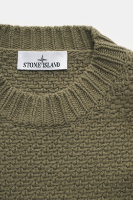 Nahaufnahme von Stone Island Rundhalspullover oliv aus RWS-zertifizierter Schurwolle und Microfaser mit voluminösem Strickbild, Rundhalsausschnitt, elastischen Rippstrickbündchen und Kompass-Badge, fotografiert von oben.