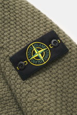 Nahaufnahme des Stone Island Rundhalspullover oliv, fotografiert von schräg oben, mit voluminösem Strickbild, Kompass-Badge am Oberarm, Strick aus RWS-zertifizierter Schurwolle und Microfaser, leicht strukturierter Griff, Regular Fit, Rundhalsausschnitt u