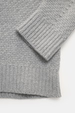 Stone Island Rundhalspullover grau, Nahaufnahme von Ärmel und Saum, Strick aus RWS-zertifizierter Schurwolle, voluminöses Strickbild, Regular Fit, Rundhalsausschnitt, Kompass-Badge am Oberarm, elastische Rippstrickbündchen, leicht strukturierter Griff.