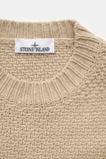 Nahaufnahme des Stone Island Rundhalspullover sand, fotografiert von oben, mit Strick aus RWS-zertifizierter Schurwolle und Microfaser, leicht strukturierter Griff, voluminösem Strickbild, Regular Fit, Rundhalsausschnitt, Kompass-Badge am Oberarm und elas