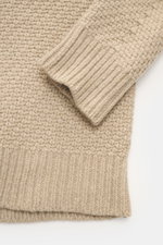 Nahaufnahme des Stone Island Rundhalspullover sand von oben fotografiert, zeigt voluminöses Strickbild, elastische Rippstrickbündchen, Strick aus RWS-zertifizierter Schurwolle und Microfaser mit leicht strukturiertem Griff.