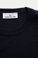 Close-up front view of Stone Island Merino Crew Neck Sweater Navy showing fine knit crew neckline and white brand label.

Description: 
<p>Timeless essential with iconic character: This STONE ISLAND crew neck sweater impresses with fine merino wool, an es
