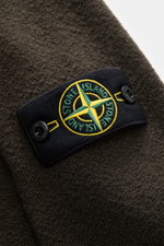 Close-up front-left view of Stone Island Crewneck Sweater 'Maglia' khaki showing compass badge on upper arm, soft wool knit.

Description: 
<p>Comfort for the cold season: The 'Maglia' sweater by STONE ISLAND impresses with soft wool quality and timeless 