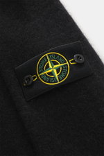 Nahaufnahme des Stone Island Rundhalspullover schwarz am Oberarm mit Kompass-Badge, weicher Wollmix, mittelfeiner Strickstruktur, elastischem Rippsaum.