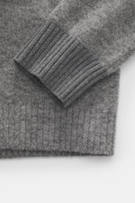Stone Island Rundhalspullover grau meliert in Nahaufnahme von oben, weicher Wollmix, mittelfeines Strickbild, elastischer Rippsaum, Kompass-Badge am Arm.