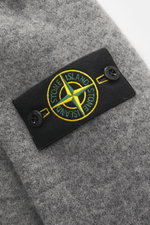 Nahaufnahme des Stone Island Rundhalspullover grau meliert mit markentypischem Kompass-Badge am Oberarm aus weichem Wollmix in mittlerer Perspektive.