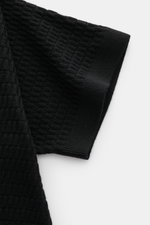Close-up top-down view of the sleeve of the Emporio Armani Short sleeve jumper black, showing its textured fine knit in pure virgin wool with ribbed bands.

Description: 
<p>Versatile companion: This lightweight short sleeve jumper in pure virgin wool by 